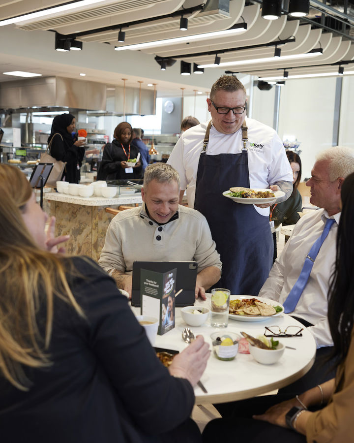 A group of employees being served food by a member of the 14forty catering team in a workplace canteen.