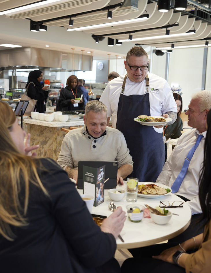 A group of employees being served food by a member of the 14forty catering team in a workplace canteen.