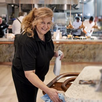 A member of 14forty's facilities management support services team cleaning a workplace canteen.